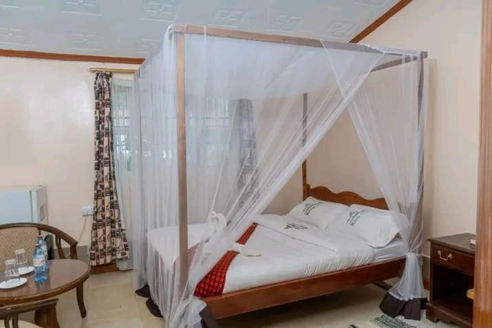 a bedroom with a canopy bed and a table at Kivu Resort in Nakuru