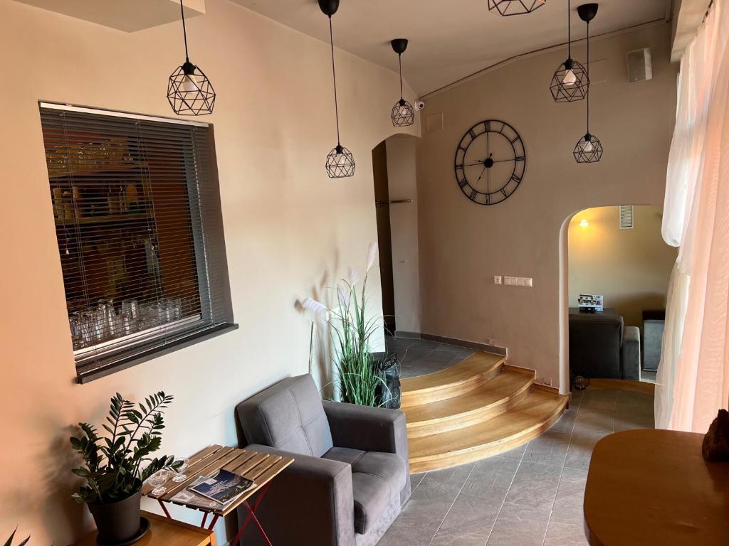 a living room with a chair and a clock on the wall at Cukrarna Guest Accommodation in Kranj