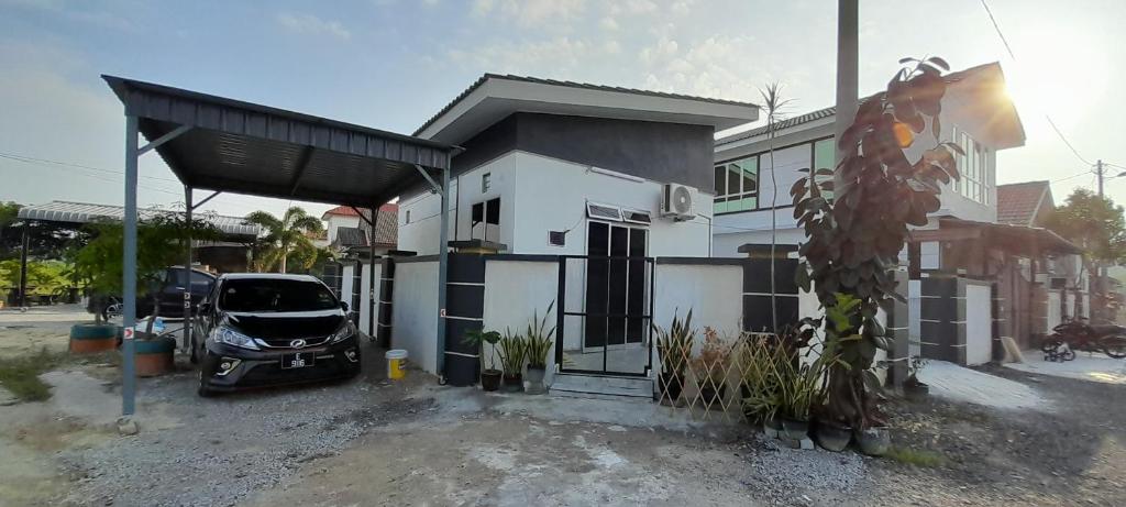 een auto geparkeerd voor een wit huis bij Studio Teratak Alisha Permatang Pauh in Permatang Pauh