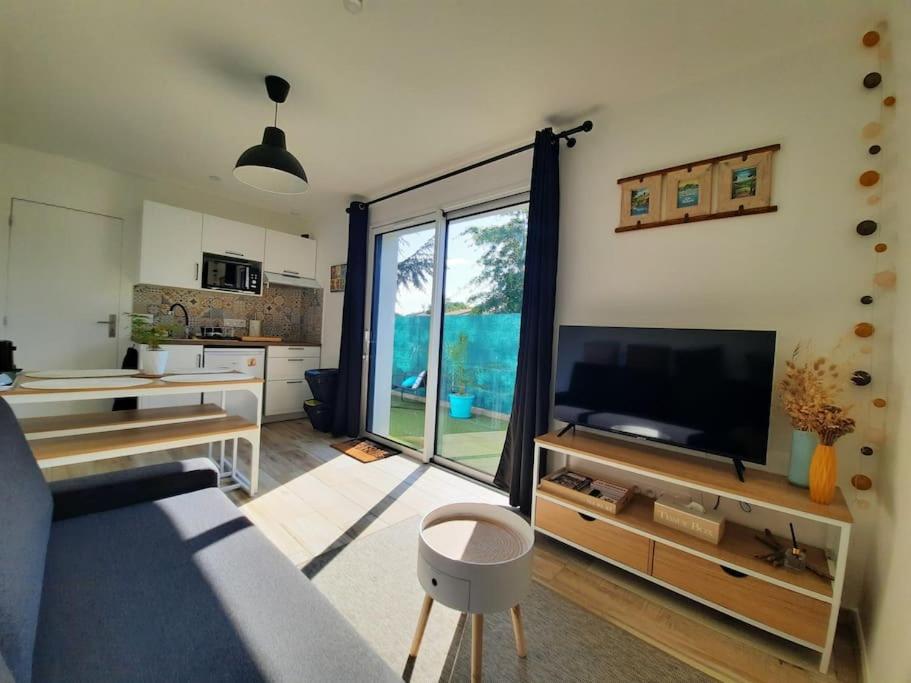 un salon avec une télévision et une grande fenêtre dans l'établissement Mon Alouette - Gîte & Bien-Être, aux Herbiers