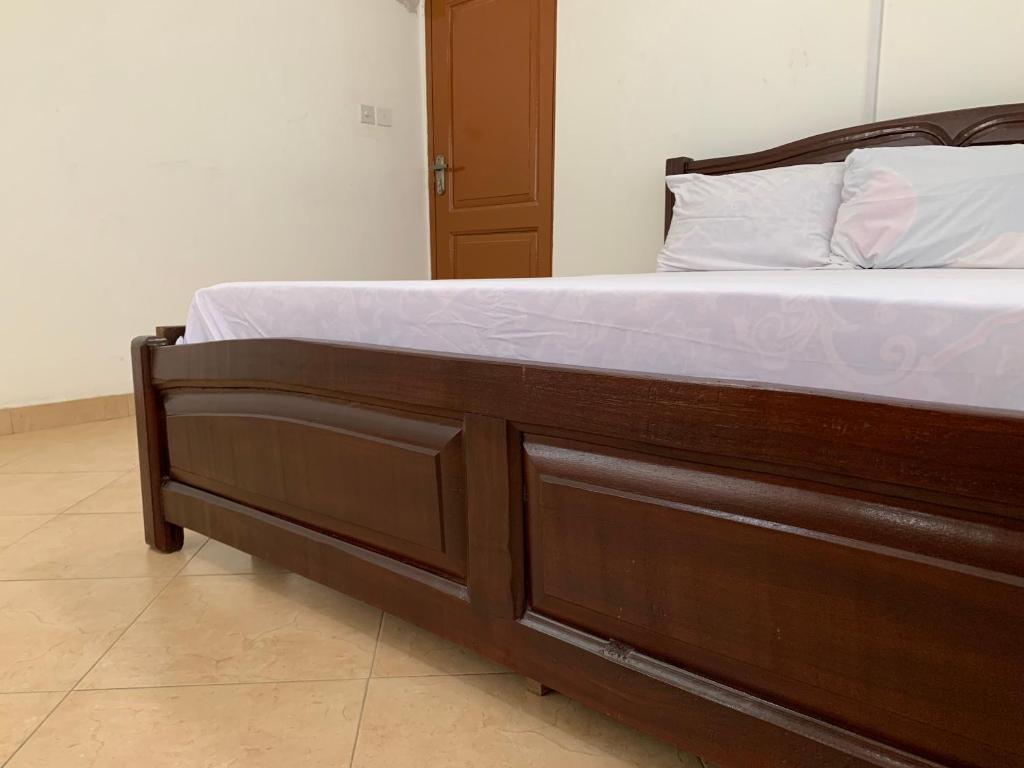 Cette chambre comprend un lit avec un cadre en bois. dans l'établissement One Cozy Bedroom in a shared apartment, à Kumasi