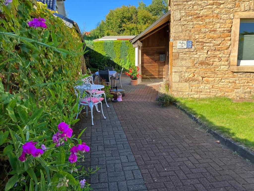 un patio con mesas, sillas y flores púrpuras en Ferienwohnung im Grünen mit Terrasse WF en Herdecke