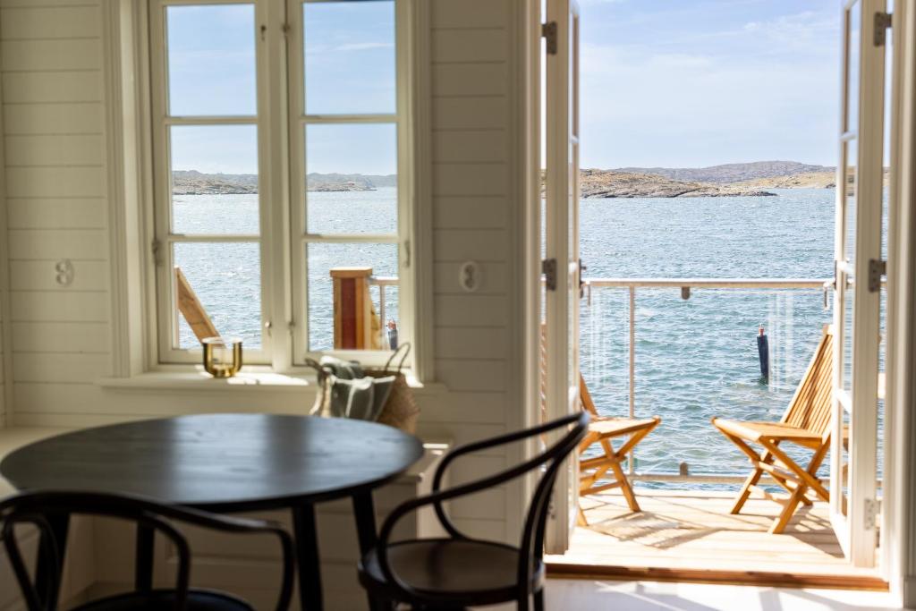 a table and chairs in a room with a view of the water at Hotel Strana in Hälleviksstrand