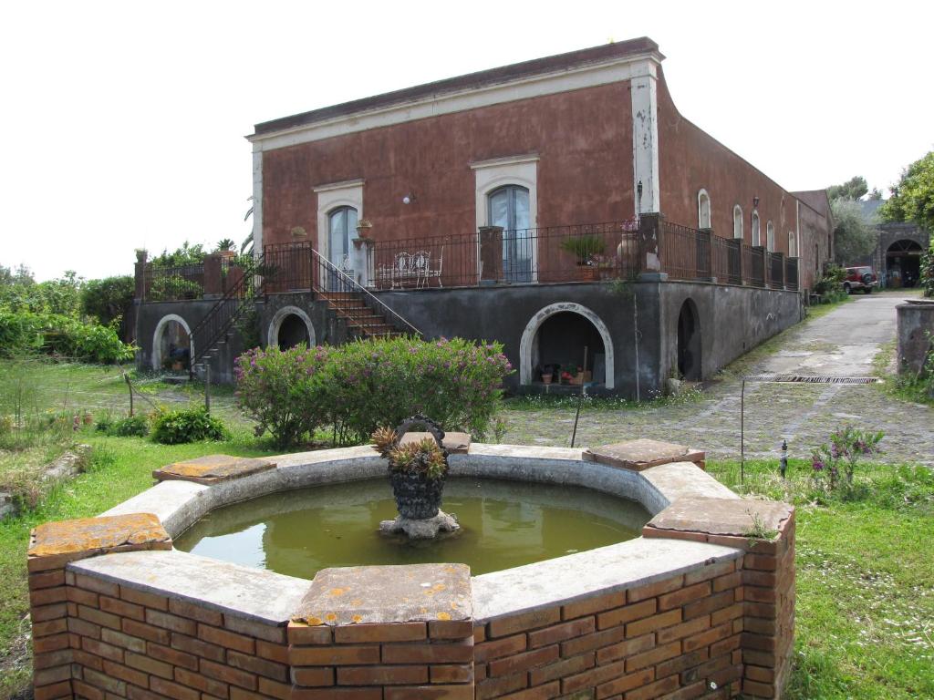 una fuente de agua frente a un edificio de ladrillo en B&B Valle Allegra, en Gravina di Catania