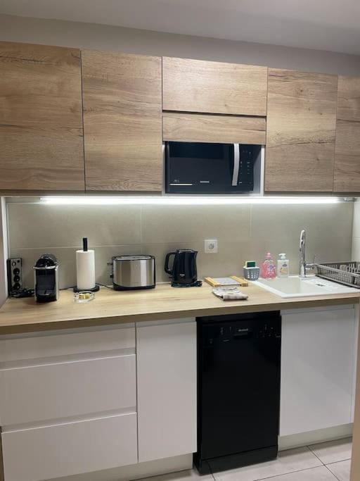 a kitchen with white cabinets and a black appliance at Appartement calme, climatisé 3min à pied de la mer in Palavas-les-Flots
