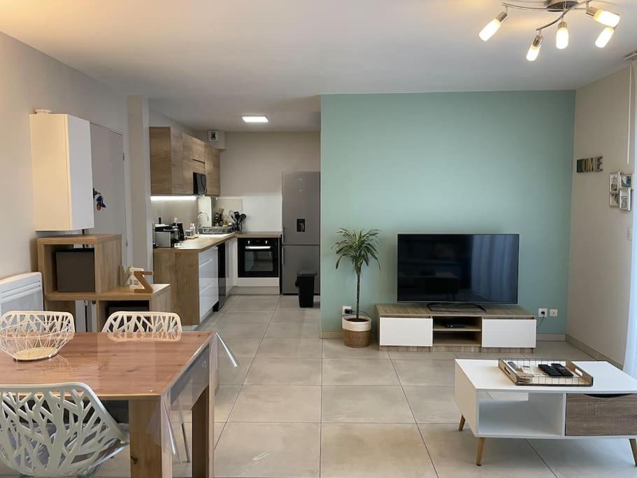 a large living room with a table and a kitchen at Appartement calme, climatisé 3min à pied de la mer in Palavas-les-Flots