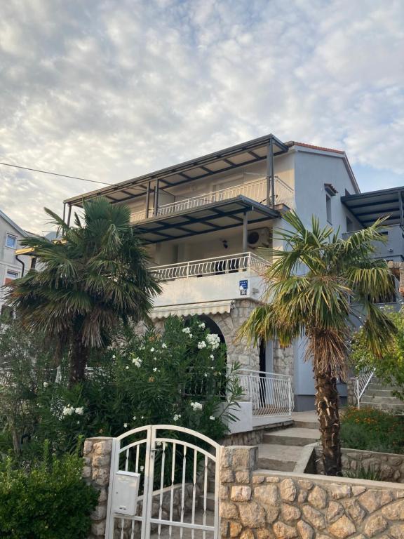 a building with a gate and two palm trees at Apartment Jasna B in Omišalj