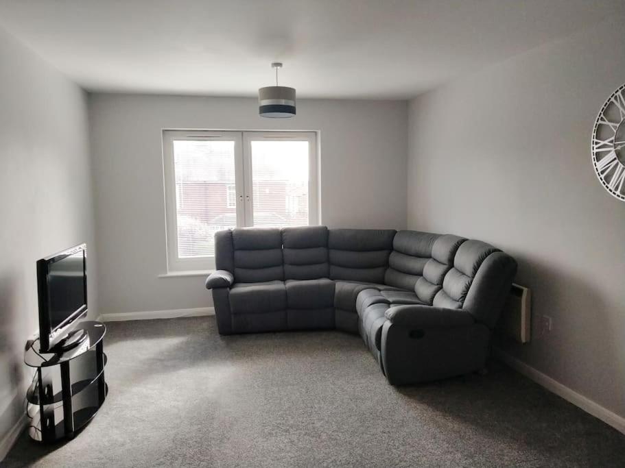 a living room with a couch and a television at Parkside Apartment Normanton in Wakefield