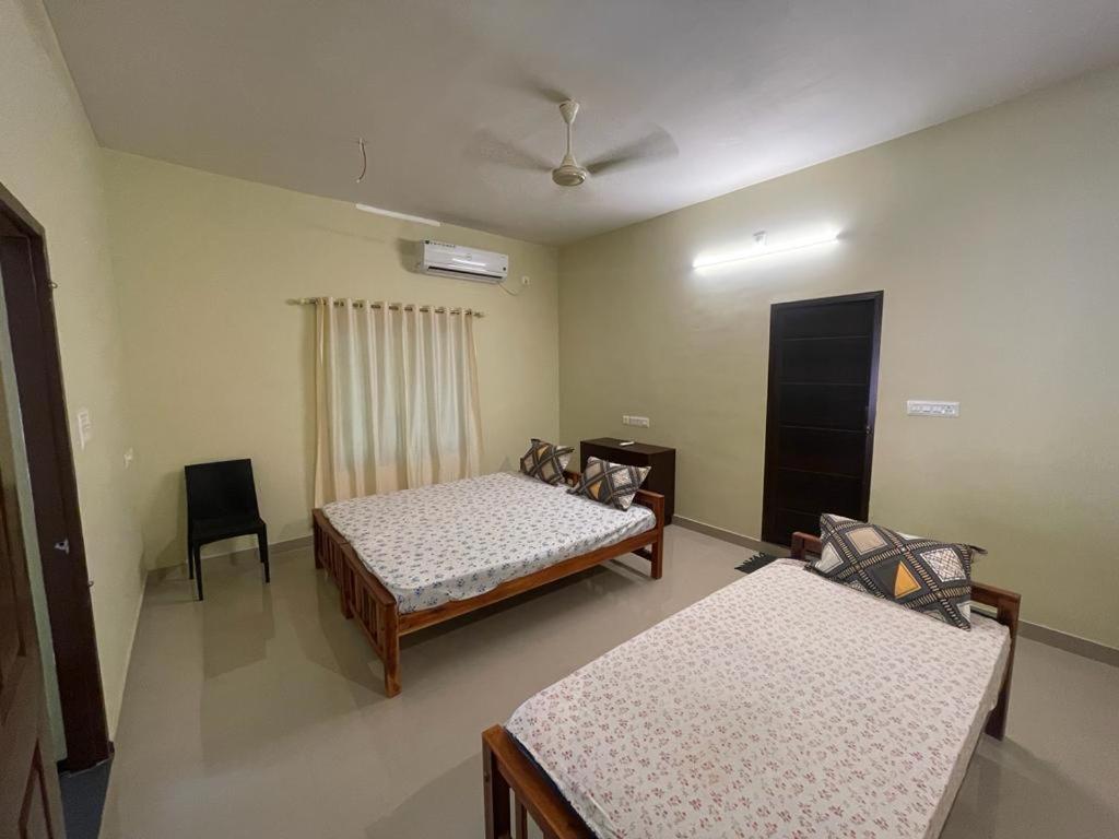 a room with two beds and a chair in it at Kalpadiyil in Bālarāmpuram