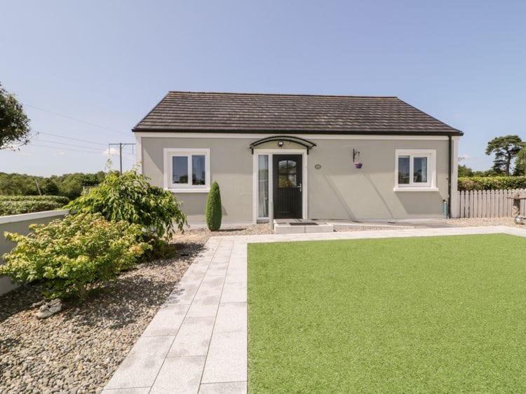 una pequeña casa blanca con césped verde en The Cottage At Arvalee Retreat, en Omagh