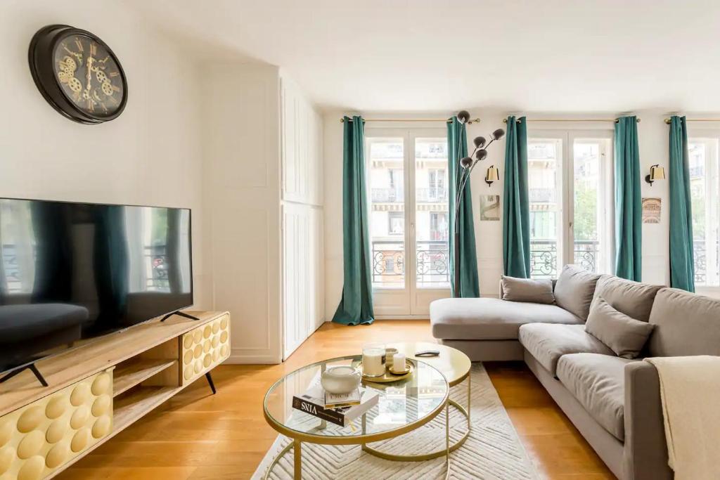 Spacious, Central & Historic Getaway - 5 Star Location في باريس: غرفة معيشة مع أريكة وتلفزيون