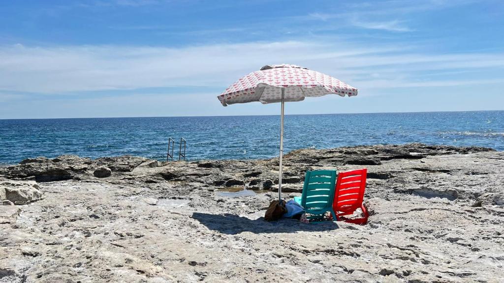 フォンターネ・ビアンケにあるVilla Anastasiaのビーチでの椅子2脚とパラソル1本