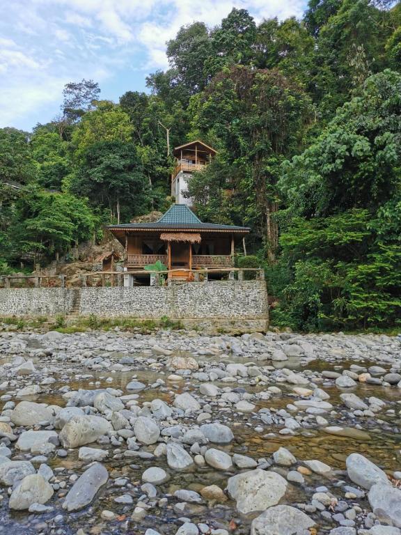 a building with a stone wall next to a river at Rambai Tree Jungle Lodges in Bukit Lawang
