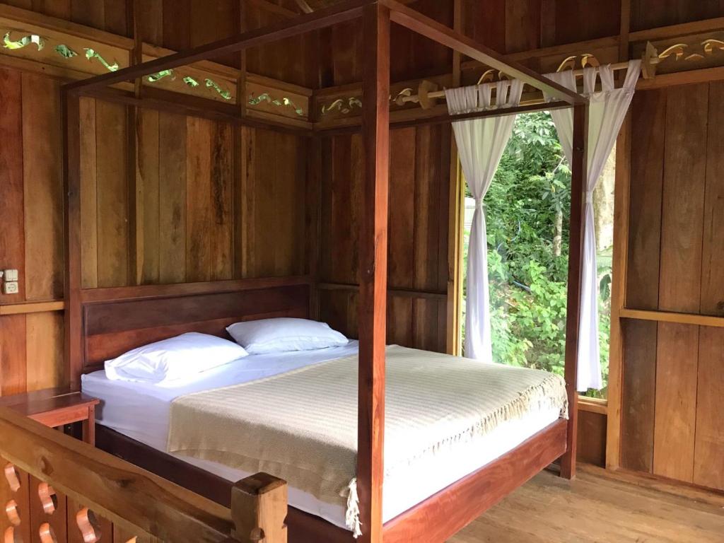 ブキットラワンにあるRambai Tree Jungle Lodgesの木造家屋内のベッドルーム(ベッド2台付)