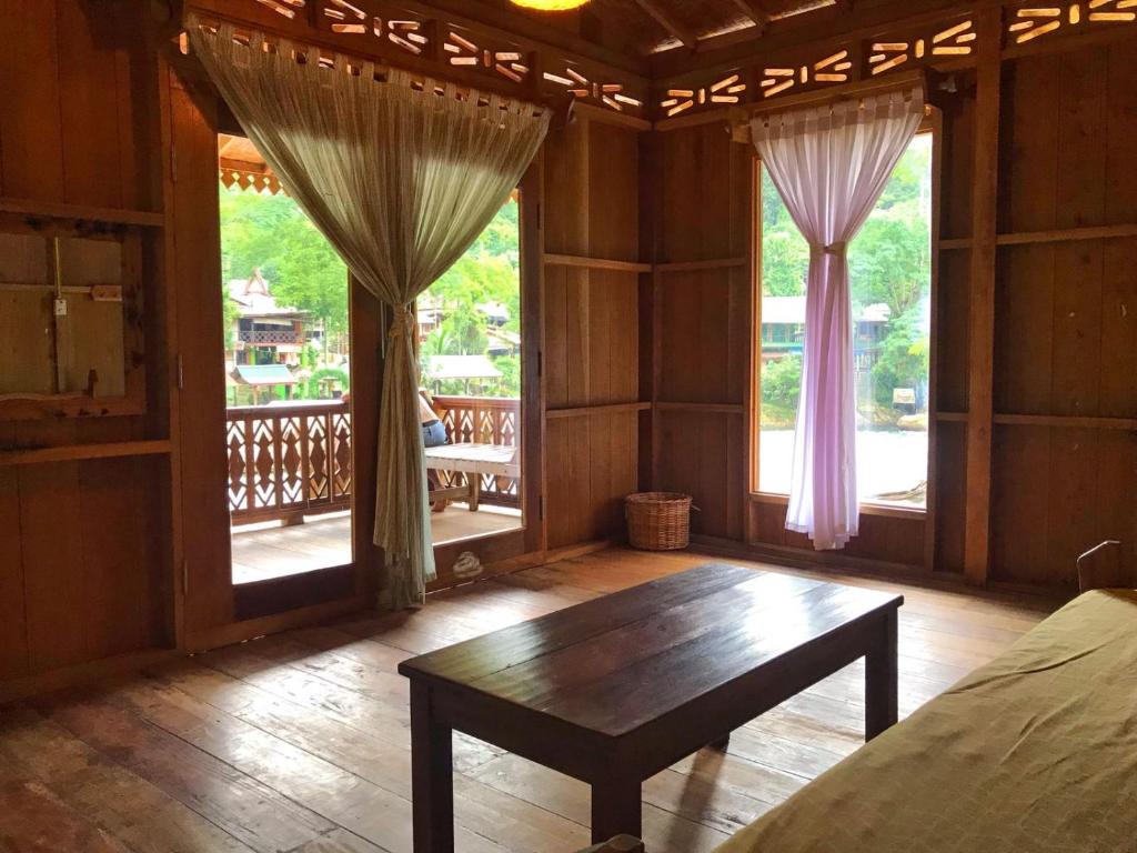 a room with a bed and a table and windows at Rambai Tree Jungle Lodges in Bukit Lawang
