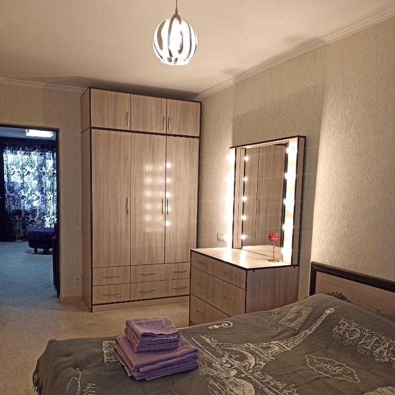 una camera con letto, cassettiera e specchio di Комфортно и уютно a Bishkek