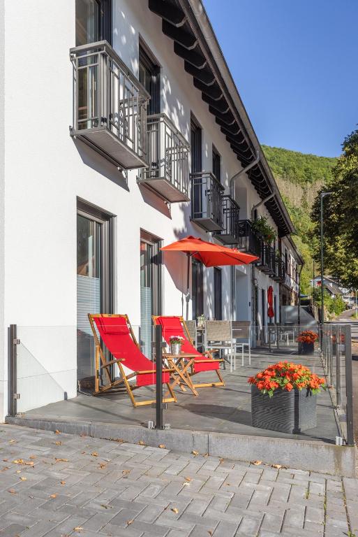 a couple of red chairs and an umbrella on a patio at Heilsteinlodge in Einruhr