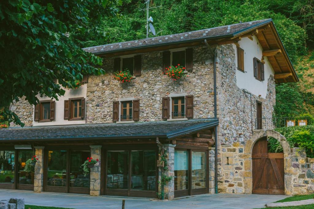 Agriturismo Ferdy في Lenna: منزل حجري كبير عليه زهور على النوافذ