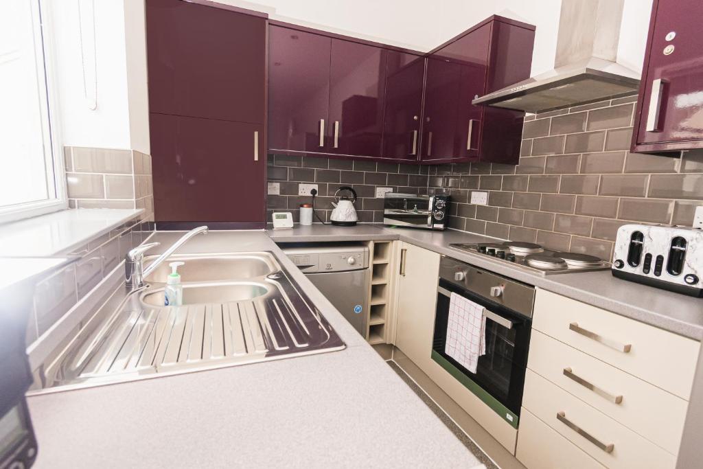 a kitchen with purple cabinets and a sink at Villette - 3 bdrm flat sleeps 5 great place for contractors in Sunderland