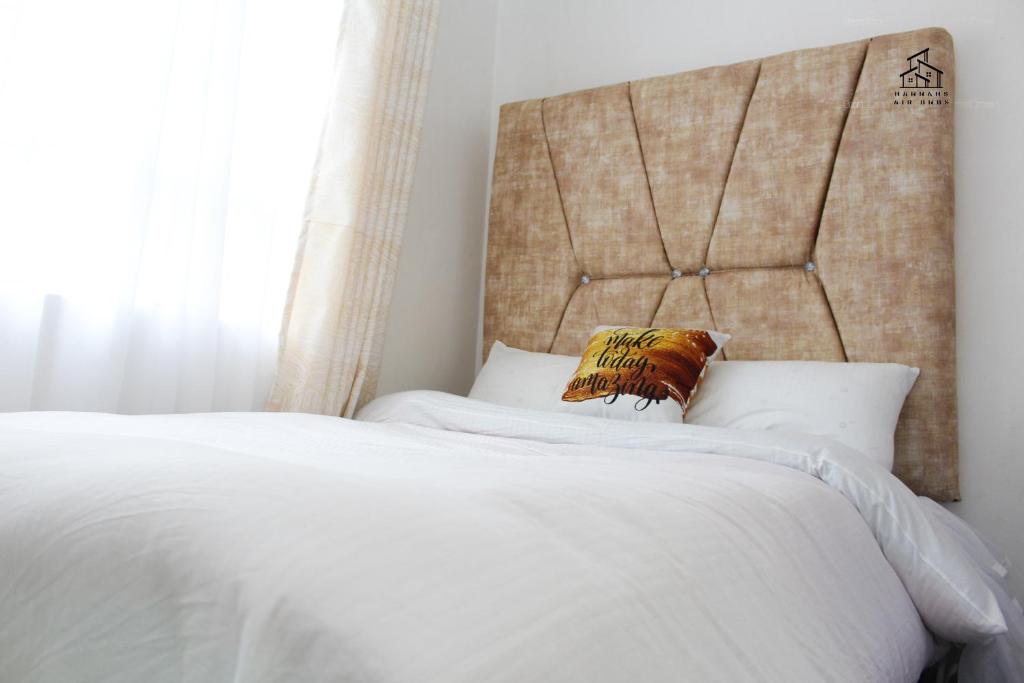 a bedroom with a white bed with a large headboard at HN airbnb in Nairobi