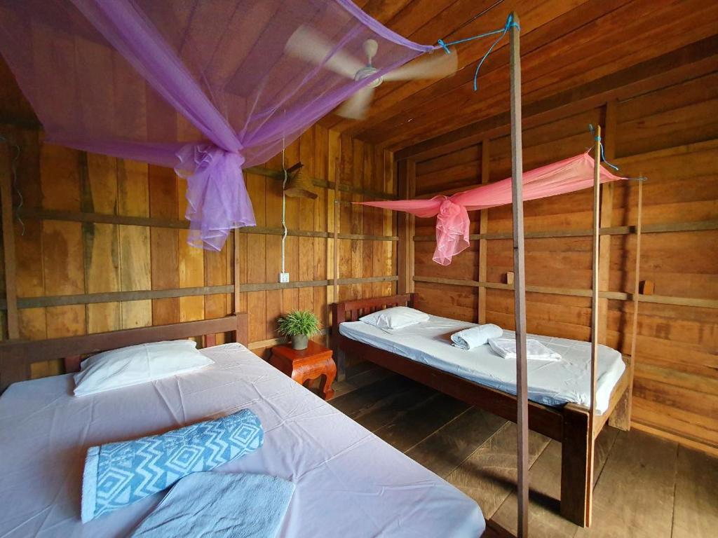 two beds in a room with wooden walls at Banlung Mountain View Treks & Tours in Banlung