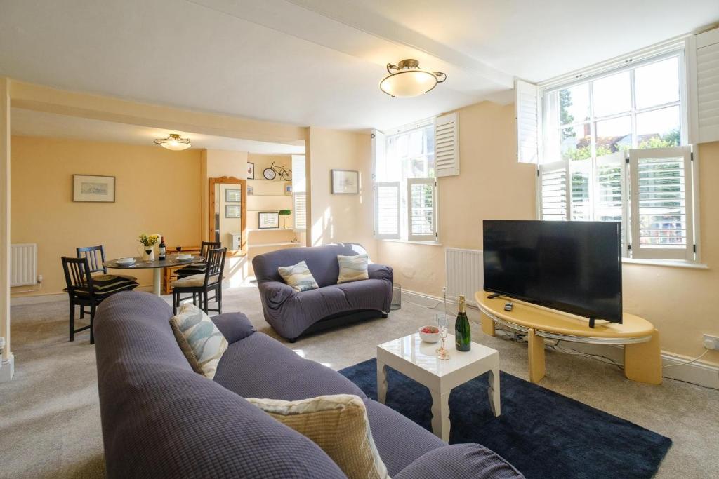 a living room with a couch and a tv at Hill House Apartment in Framlingham