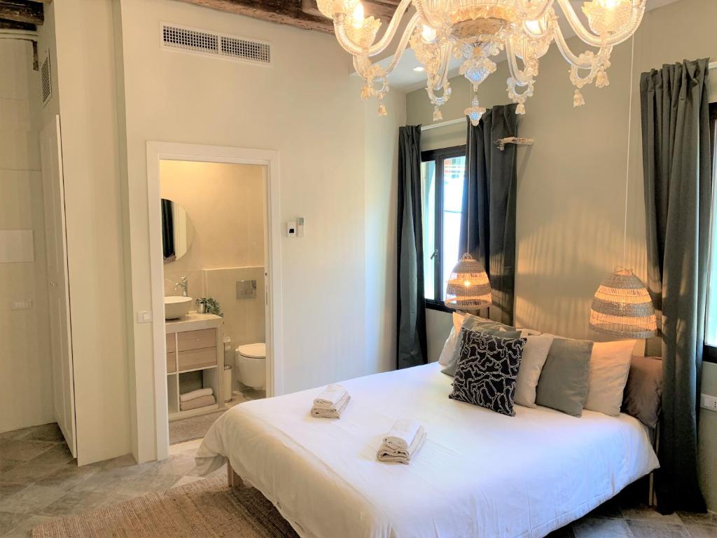 ein Schlafzimmer mit einem großen weißen Bett mit einem Kronleuchter in der Unterkunft Mini Suite in Chioggia