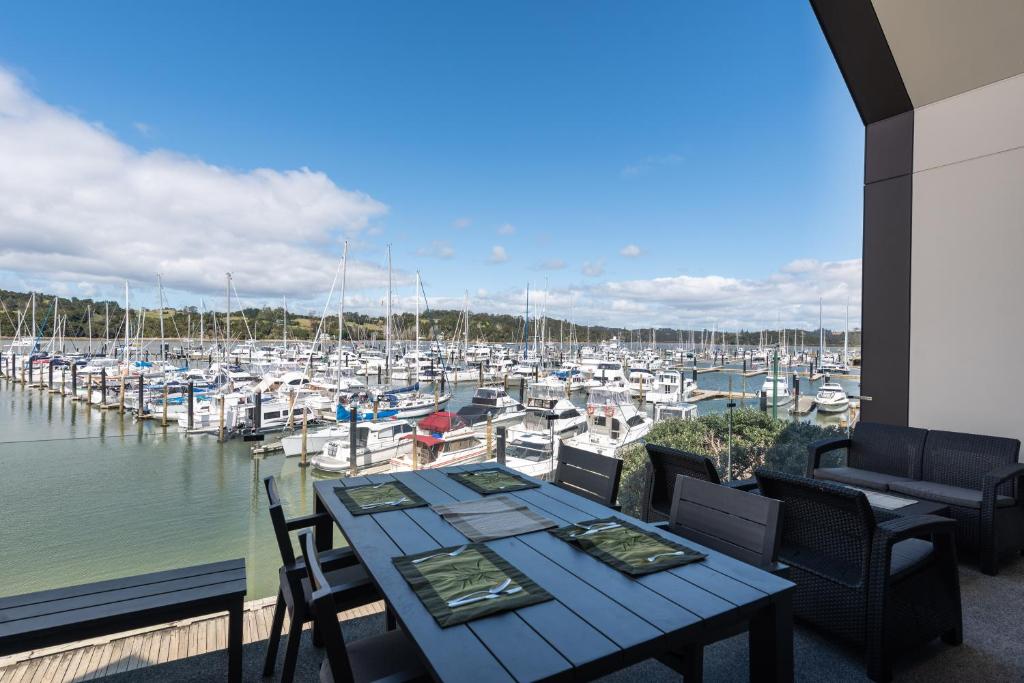 eine Terrasse mit einem Tisch und Stühlen sowie einem Yachthafen in der Unterkunft Bay of Islands Apartment with Marina Views in Opua