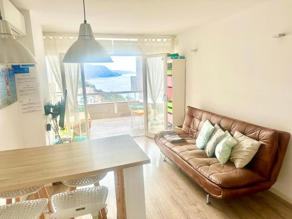 ein Wohnzimmer mit einem braunen Ledersofa und einem Tisch in der Unterkunft Cala Salions, Chalana II in Tossa de Mar