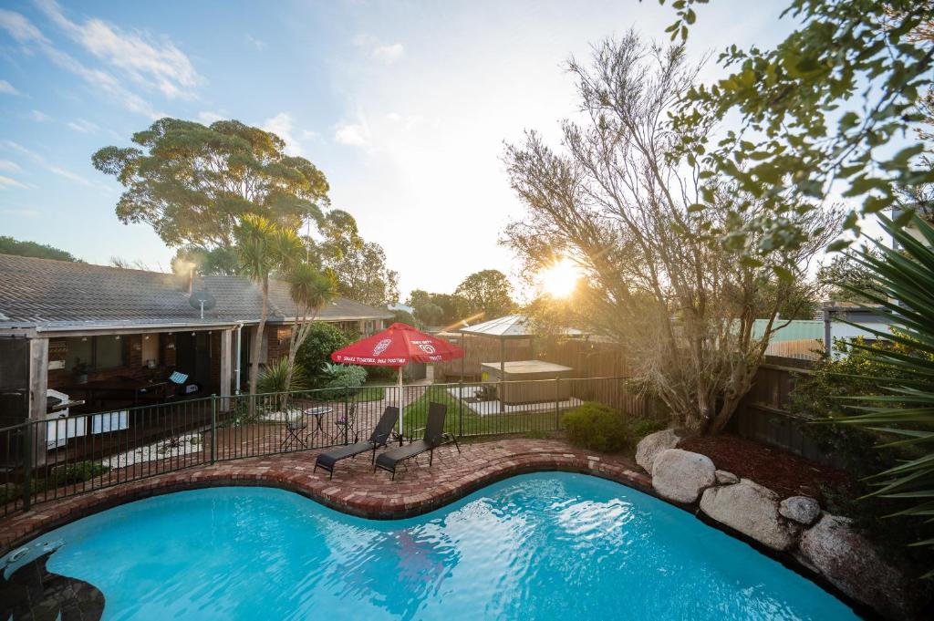 a swimming pool in a yard with a red umbrella at Fun Filled Renovated 80's Gem, 400m to Beach! in Torquay