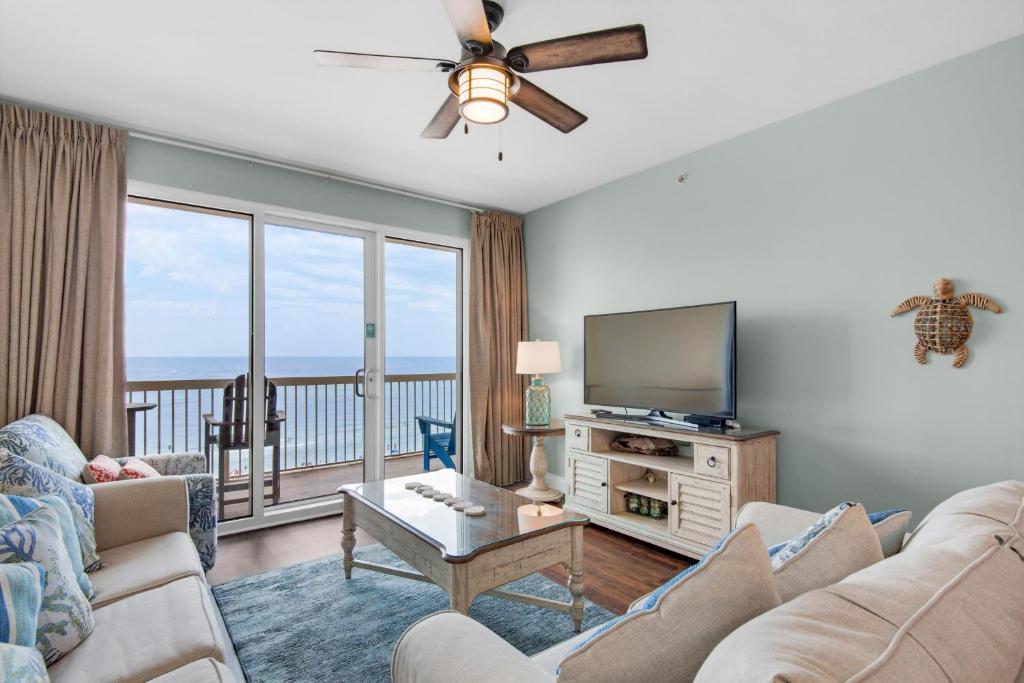 ein Wohnzimmer mit einem Sofa, einem TV und einem Balkon in der Unterkunft Calypso 1-608 East in Panama City Beach