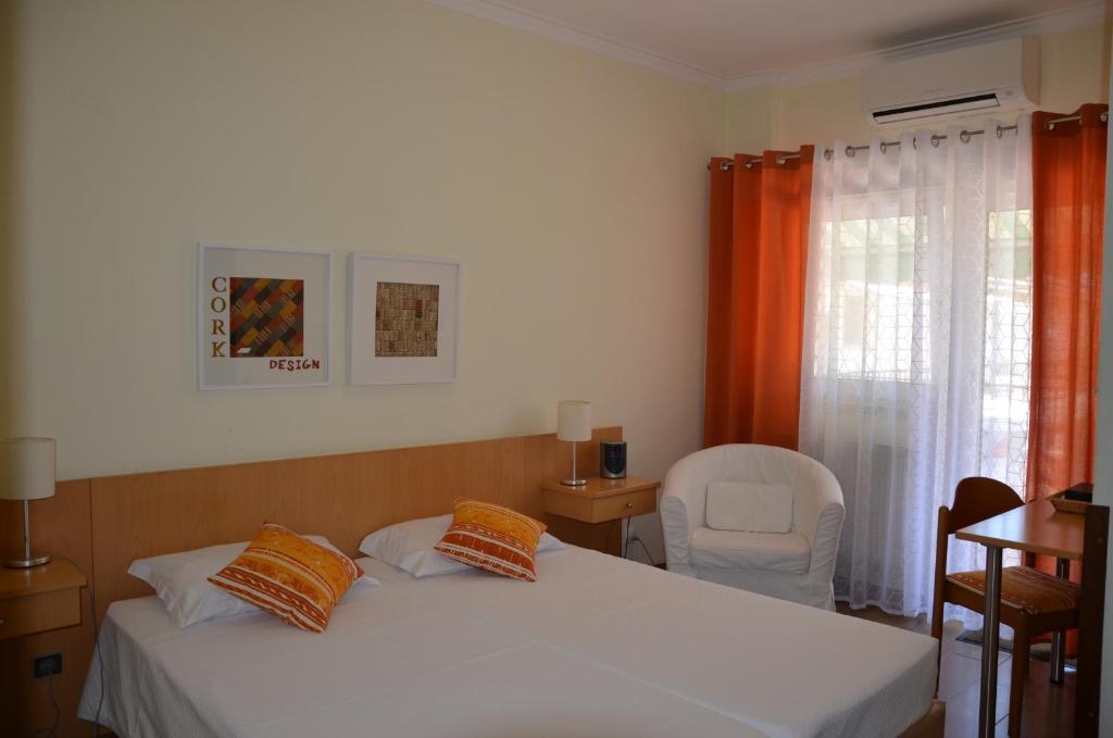 a bedroom with a bed and a chair and a window at ABLA Guest House in Carcavelos