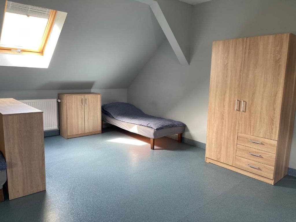 Cette chambre mansardée comprend un lit et des placards en bois. dans l'établissement Lawendowa Przystań - Apartament, 
