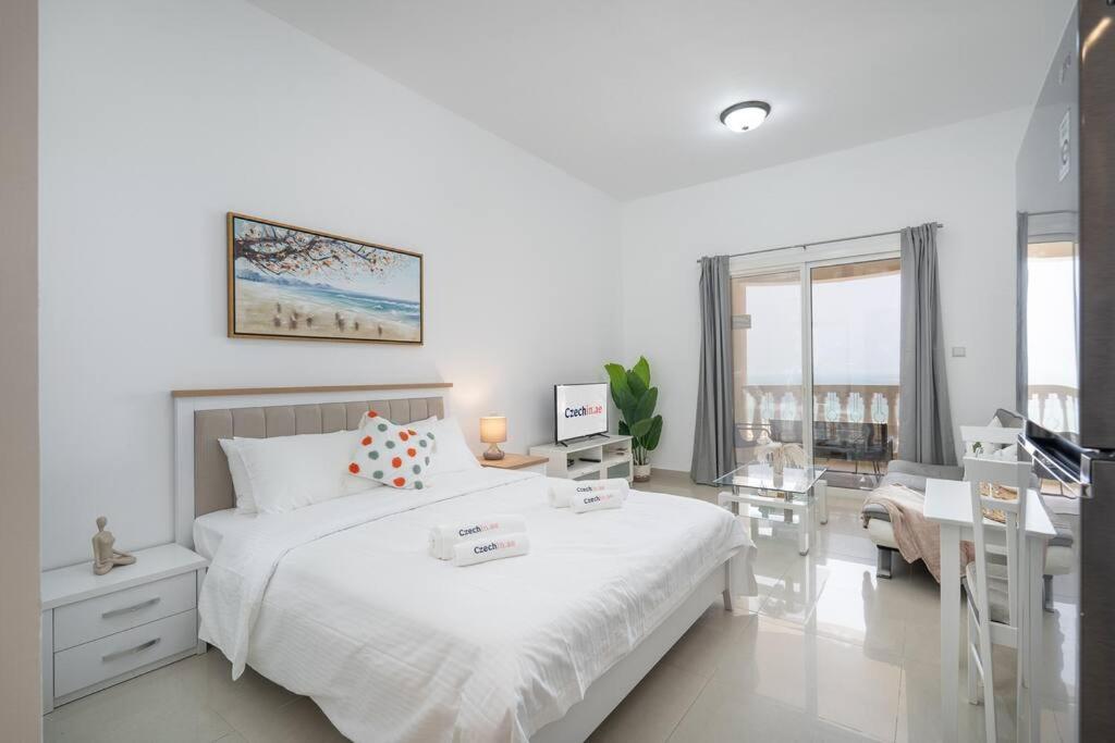 a white bedroom with a bed and a desk and a desk at Serene Studio & Sea View & Brand New Listing in Ras al Khaimah