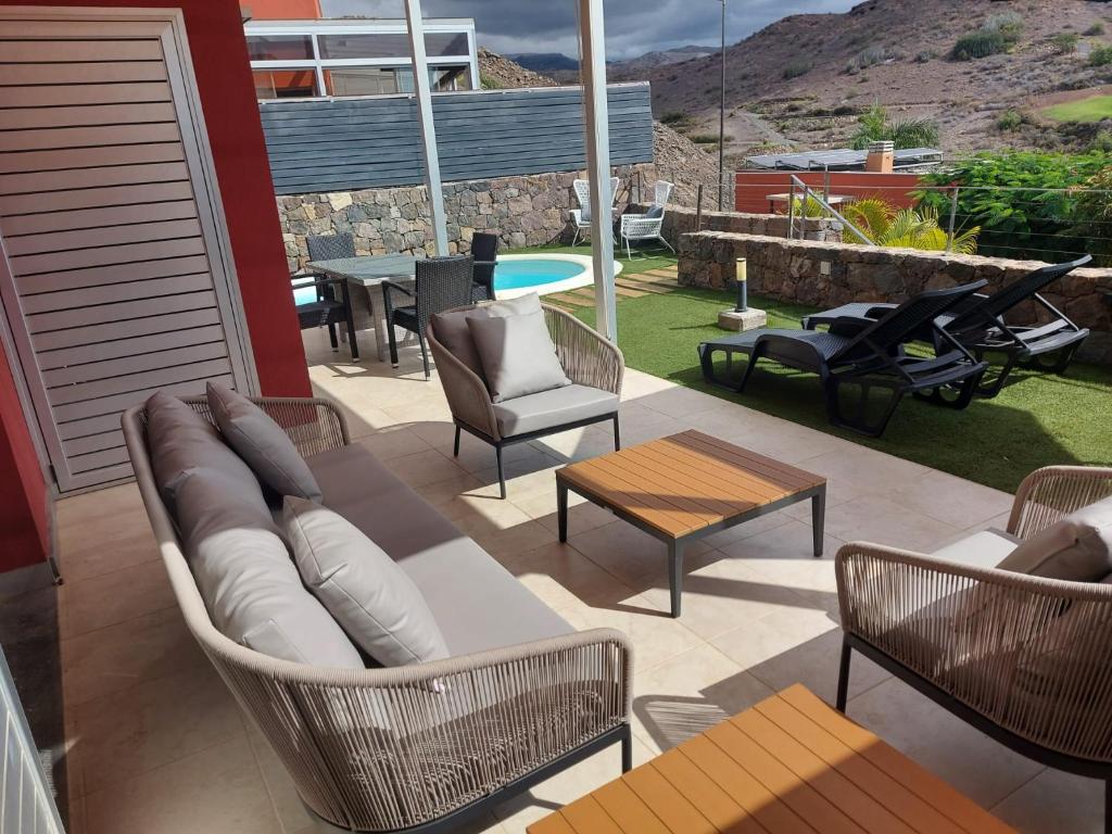 a patio with a couch and chairs and a table at Villa Vista Golf Salobre - Maspalomas self-sufficient with pool heating in Maspalomas