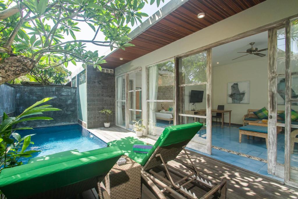 a patio with a pool and chairs and a living room at Sari Dana Villas in Sanur