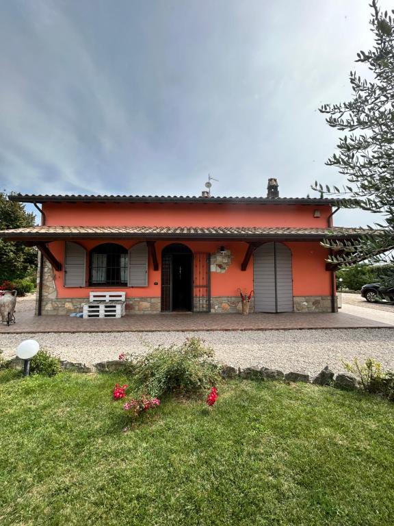 una piccola casa arancione con una panchina davanti di La Perla di Assisi ad Assisi