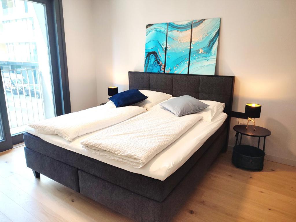 a large bed in a bedroom with a painting on the wall at Design Apartment Vienna City Center - free parking! in Vienna