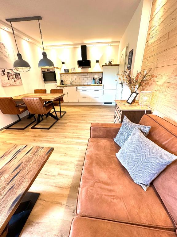 a living room with a brown couch and a kitchen at Ferienwohnung Auszeit Norddeich I 5 Minuten zu Fuß zum Meer in Norddeich