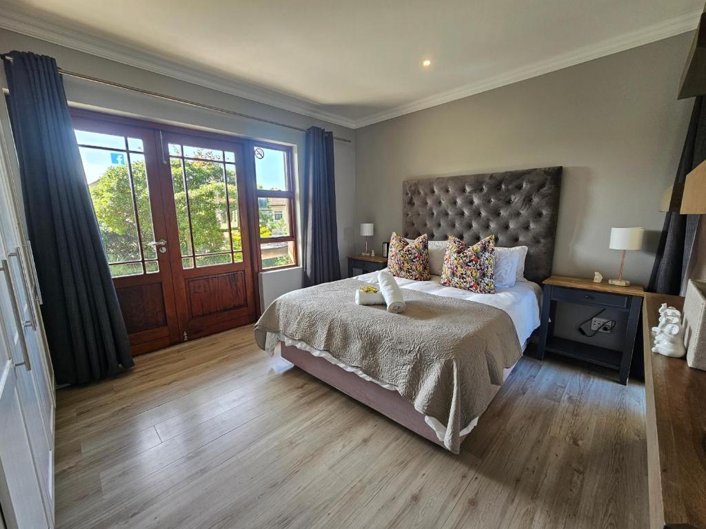 a bedroom with a large bed and a large window at Six Whale Rock Gardens with back up power for load shedding in Plettenberg Bay