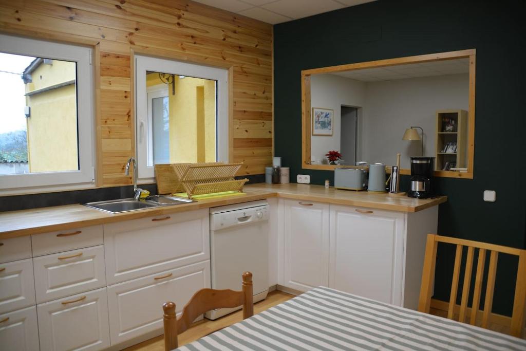 eine Küche mit weißen Schränken und einem Waschbecken und einem Tisch in der Unterkunft Apartament rural Can Ramon in Estanyol