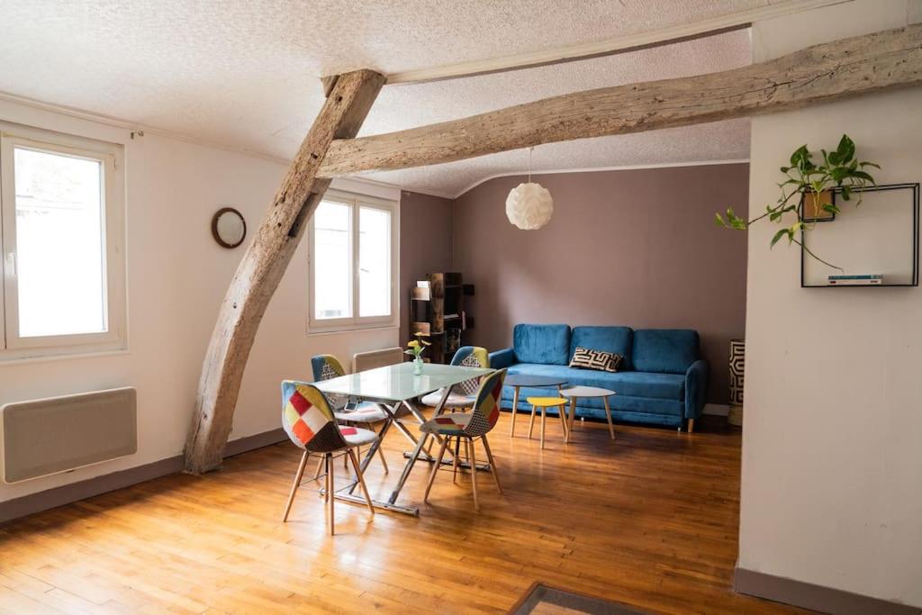 a living room with a table and a blue couch at Gîte en centre historique 65m2 in Beaugency