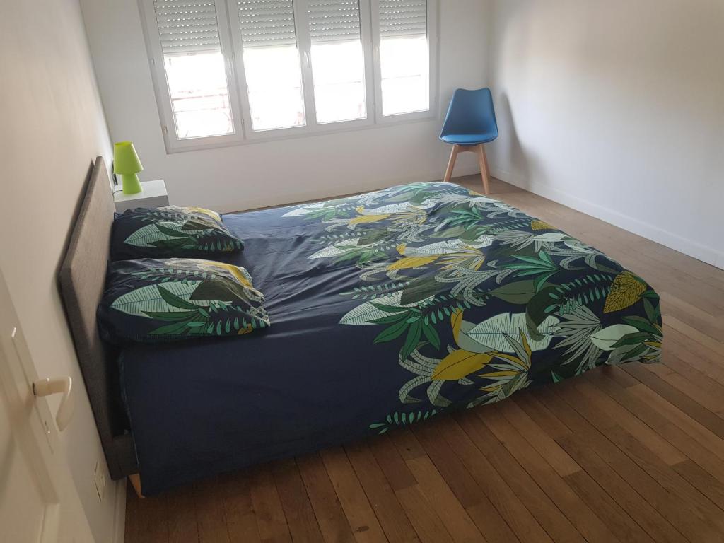 a bedroom with a bed with a blue bedspread with leaves at Appartement centre d Arcis in Arcis-sur-Aube