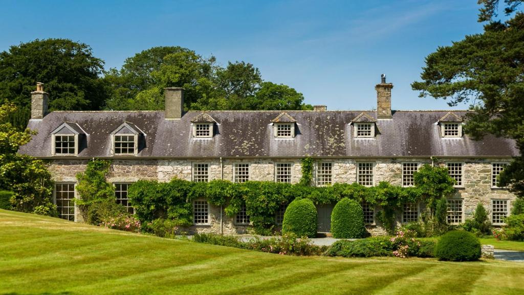 una antigua casa de piedra con un patio verde en Ty Fry Manor, en Pentraeth
