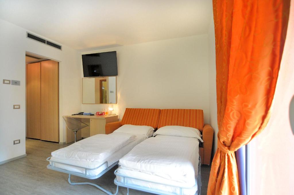 two beds in a room with an orange curtain at Eco Hotel Cleofe in Caorle