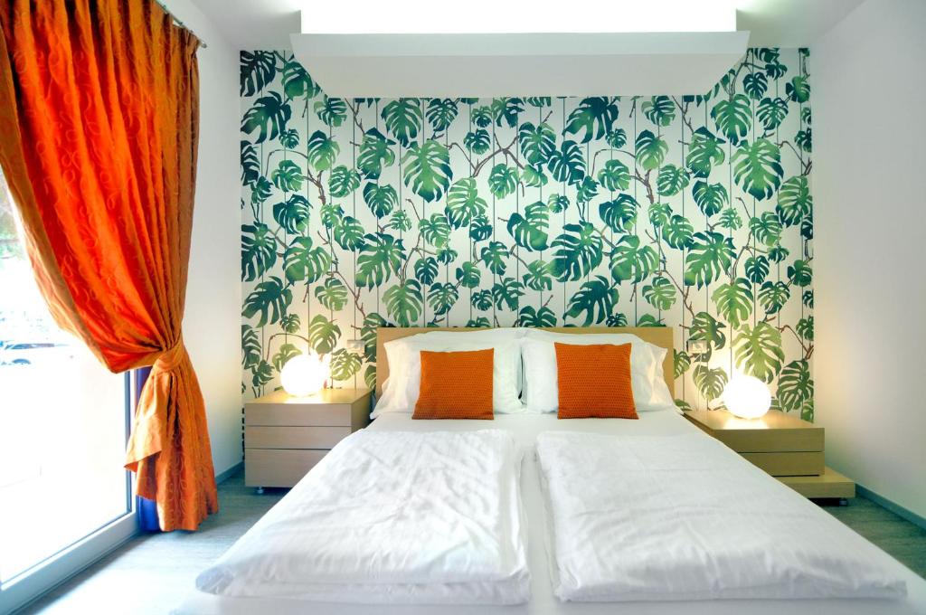 a bedroom with a bed with orange pillows and wallpaper at Eco Hotel Cleofe in Caorle