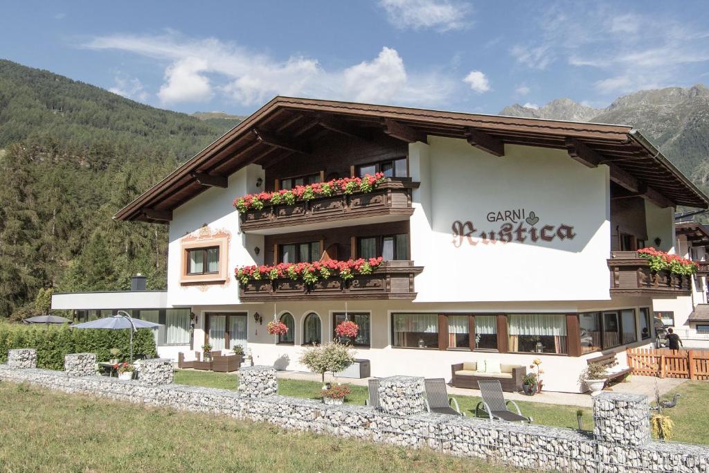 um grande edifício branco com flores na varanda em Garni Rustica em Sölden