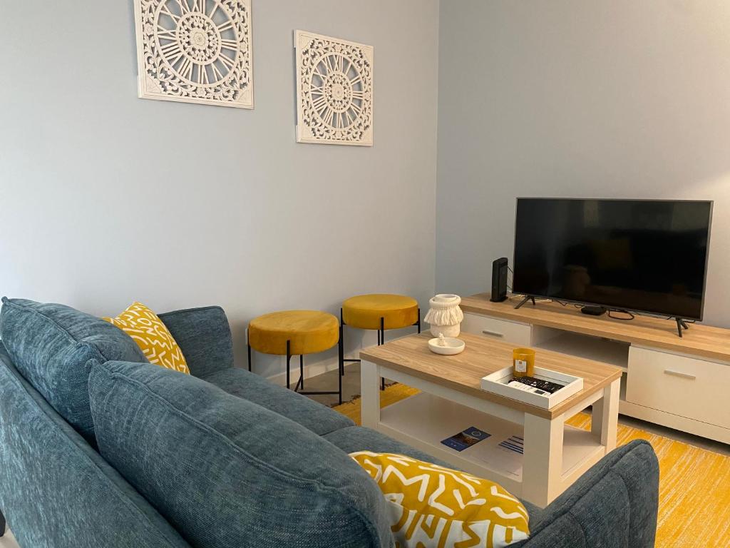 ein Wohnzimmer mit einem blauen Sofa und einem Fernseher in der Unterkunft Casa do Mar - Ribeira Quente Azores in Ribeira Quente