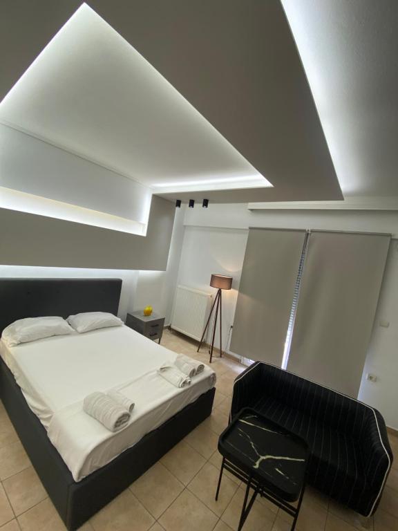 - une chambre avec un lit blanc et une chaise noire dans l'établissement Central appartment3 with parking, à Larissa