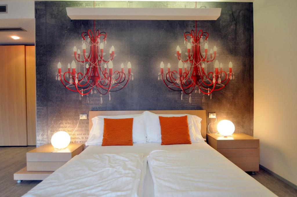 a bedroom with a large bed with two chandeliers at Eco Hotel Cleofe in Caorle